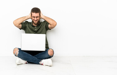 Young man sitting on the floor frustrated and covering ears