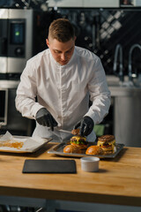 Chef prepares delicious hamburger in professional kitchen burger with beef patty cheese tomato...