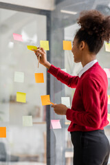 Young mixed african american businesswoman with afro hairstyle  planning on whiteboard  in a...