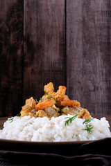 Fish curry with codfish, pollack and shrimps with coconut milk served on rice on brown plate