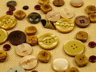 Obraz premium Brown buttons in different designs and sizes for sewing to clothes lie on the brown burlap. 