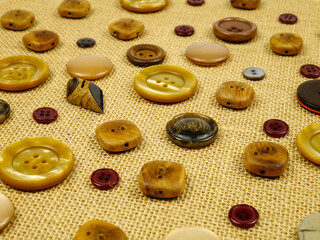 Obraz premium Brown buttons in different designs and sizes for sewing to clothes lie on the brown burlap. 