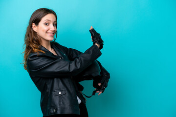 Naklejka premium Young caucasian woman with a motorcycle helmet isolated on blue background pointing back