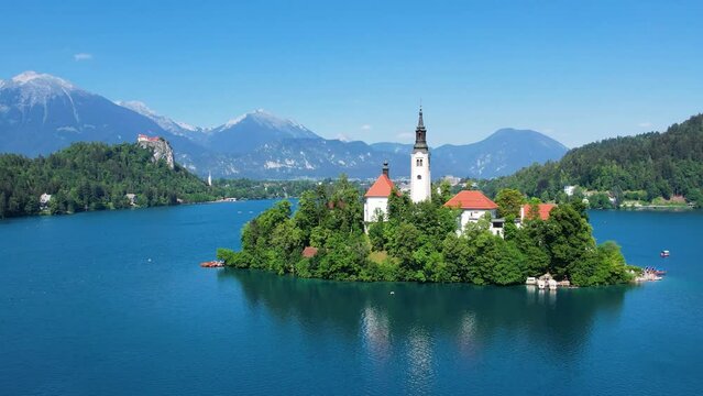 Pilgrimage Church of the Assumption of Mary In Lake Bled, Slovenia. Summer blue lake and mountains in background. Orbiting shot.