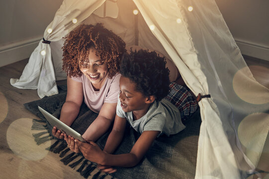 Black Family, Tablet And Mother With Kid In Tent At Night Watching Movie, Video And Having Fun In Home. Technology, Bokeh And Smile Of Happy Mixed Race Mom Bonding With Boy Child While Streaming Film