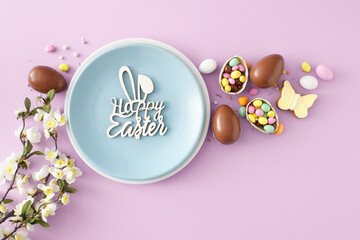 Easter decor concept. Flat lay photo of chocolate eggs dragees gingerbread spring blossom flowers and blue plate with inscription happy easter on isolated lilac background
