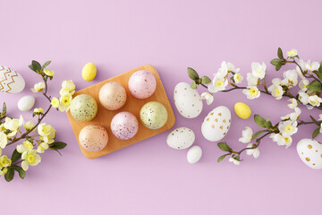 Easter celebration idea. Top view photo of colorful easter eggs in wooden holder and spring blossom branch on pastel lilac background. Easter concept