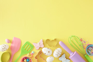 Easter concept. Top view composition of white golden eggs kitchen utensils baking molds butterfly cookies and сolorful dragees on isolated yellow background with copyspace