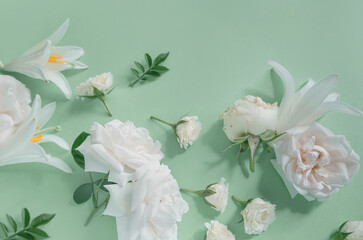 Creative summer composition made of rose and lily flowers on pastel green background. Beautiful...