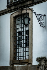 Lamp details on barred window of old building in Braga, Portugal