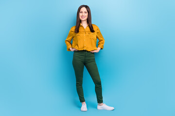 Full length photo of cheerful positive lady dressed yellow shirt standing hands arms waist isolated blue color background