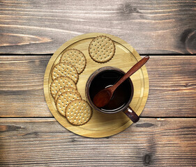 A mug of drink with a wooden spoon, cookies on a wooden tray. Wooden background. Top view, flat lay.