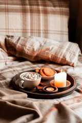Warm cozy bedroom interior with cup of hot chocolate on tray, candles