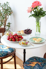 Breakfast served on marble table. Tea, fresh strawberry, cottage cheese pancakes, cherry and vase with flowers