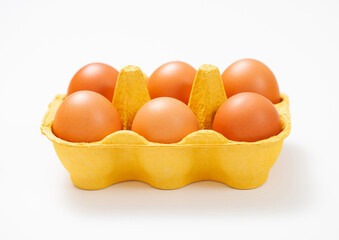 Brown raw organic eggs in yellow paper tray on white background