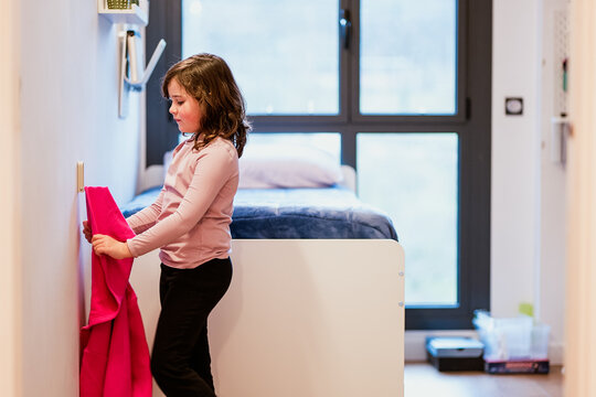 Girl hanging hoodie on hanger in bedroom