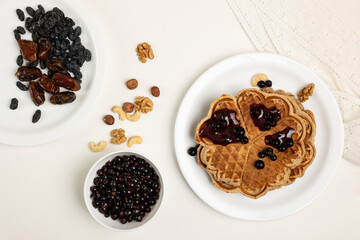 Waffles with jam, berries and nuts on the table.