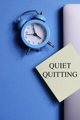 quote Quiet quitting on yellow sticker on computer with clock on blue background. work life balance concept. post covid life philosophy.