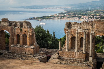Ancient town Taormina in Sicily, Italy with antique theatre in Mediterranean and port