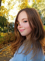 Fototapeta premium Cute little girl in autumn park holding bunch of yellow leaves. High quality photo