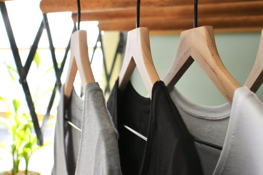 Simple basic t-shirts tee shirts hanging on wooden hangers in a laundry room on wash day.