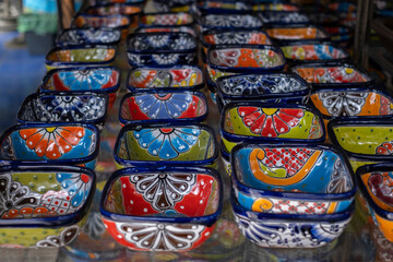 Close up of many colorful ceramic snack and sauce bowls arranged in rows at a local souvenir craft...