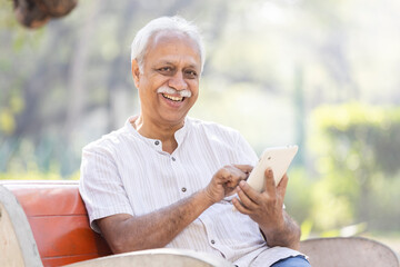 Happy senior men using digital tablet at park