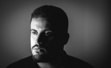 Grayscale portrait of a young Caucasian male with a serious face looking aside