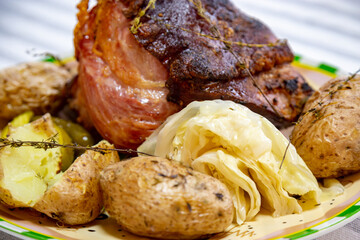 Roasted smoked pork knuckle with typical side dishes, traditional German dish, isolated portrait in selective focus.