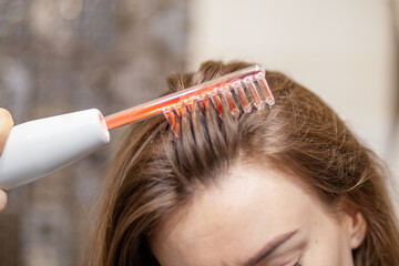 Woman uses darsonval for massage head's skin. Receiving electric darsonval facial massage procedure. Face Beauty Treatment. Darsonval Therapy Using High Frequency D'Arsonval, Skin Care Device . 