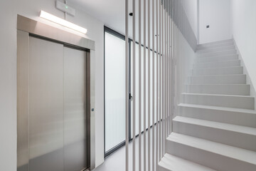 Modern high-tech style in the entrance of a new house or office building with an elevator, staircase and panoramic window. Concept of new buildings with a developed modern structure