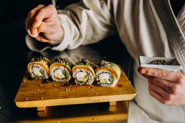 Sushi master makes fresh appetizing sushi. Sprinkle sesame seeds on top of the rolls.
