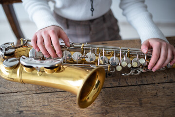 Fototapeta premium Young woman assembling a saxophone to start playing music.