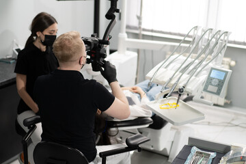 Fototapeta premium Dentistry a dentist examines a patient through a microscope