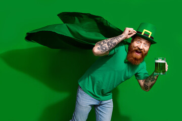 Photo of cool impressed man wear t-shirt leprechaun cap enjoying beverage isolated green color...