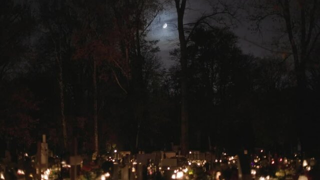 All Saints Day at the cemetery with candles at night under the Moon.