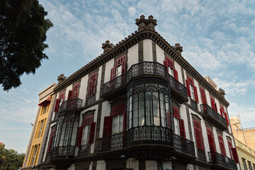 Corner view of white building with ornate windows and red shutters in old town in the city of Las Palmas de Gran Canaria, Spain