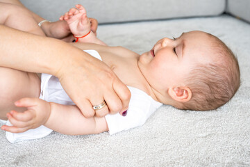 Side view naked boy or girl, lying on back. Unrecognised female hands touching baby. Tactile...