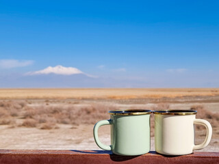 Two enameled cups of coffee or tea in the autumn landscape outdoors.Two enamel mugs in the...