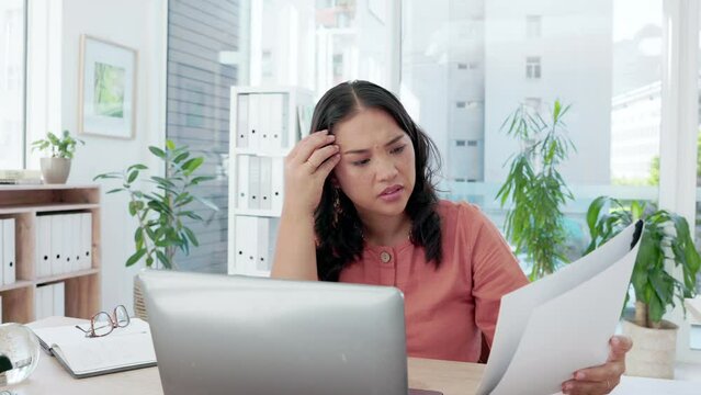 Asian woman, laptop and confused and thinking with documents in planning or strategy on office desk. Female employee in thought or wondering with paperwork on computer for project plan or idea