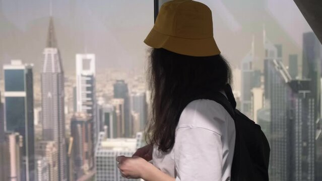 a girl looks out the window at the center of Dubai, a woman looks out the window at the skyscrapers, the center of Dubai from the top