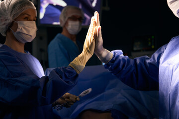 Doctors in operating room give high five after successful operation