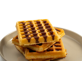 Chocolate waffles on a plate isolated on white background. Waffles in chocolate. Close-up.