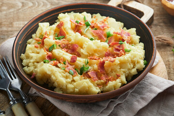 Mashed potatoes. Bacon mashed potatoes with green onion, pepper and cheddar cheese in bowl on old wooden backgrounds. Delicious creamy mashed potatoes. Top view.