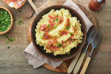 Mashed potatoes. Bacon mashed potatoes with green onion, pepper and cheddar cheese in bowl on old wooden backgrounds. Delicious creamy mashed potatoes. Top view.
