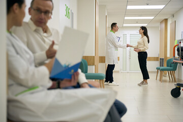 Obraz premium Background, handshake between a doctor and patient in hospital corridor