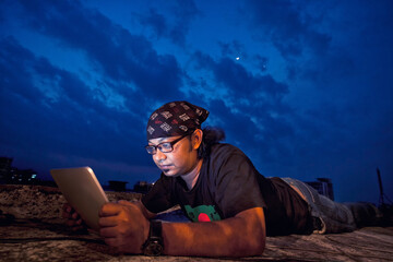 South Asian Man Working on a Tablet Under Night Sky