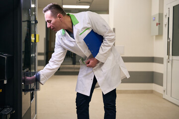 Health worker stands in the lobby at the coffee machine