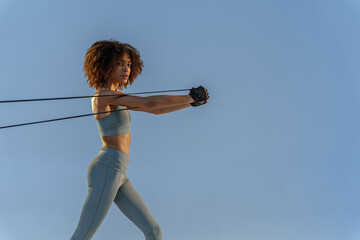 Sporty woman performs exercises for muscles of hands use expander on studio background