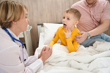 Neat toddler child demonstrating throat to the doctor in the medicine clinic